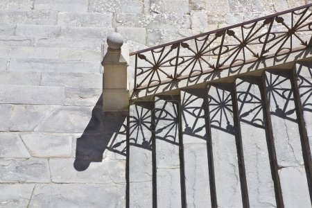 Foto de Concepto de barreras arquitectónicas con escalera de piedra vieja con barandilla de hierro forjado y pavimentación de piedra - Imagen libre de derechos