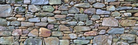 Old traditional aged and cracked stone wall made with large stone blocks 