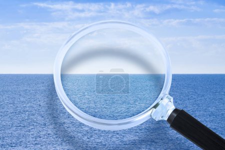 Magnifying glass against a calm ocean - Research, observation and surveillance concept - Discovering the unknown