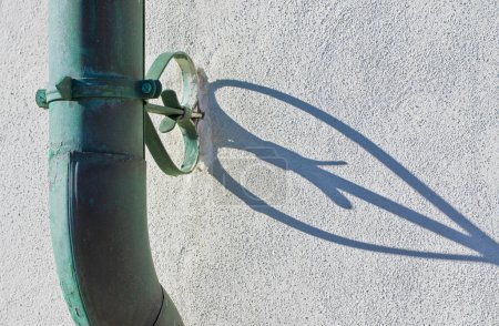 Foto de Antiguo tubo de cobre oxidado oxidado contra una pared de yeso con sombra - Imagen libre de derechos