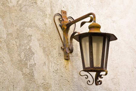 Lampadaire italien rouillé du XIXe siècle contre un mur de plâtre  