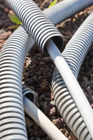 Flexible Kunststoff-Pipeline mit Stromkabel aus dem Boden in einer Baustelle