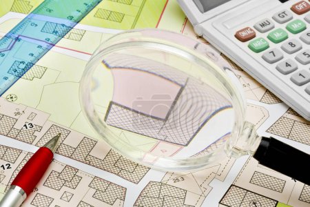 Imaginary cadastral map with buildings, land parcel and vacant plot - property registry and real estate concept seen through a magnifying glass - note: the map background is totally invented and does not represent any real place