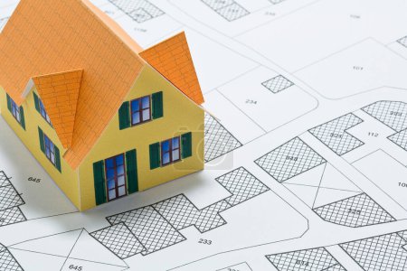 Katasterplan mit Gebäuden, Baugrundstück und freien Grundstücken für Hausbau - Bautätigkeit und Genehmigungskonzept mit Hausmodell