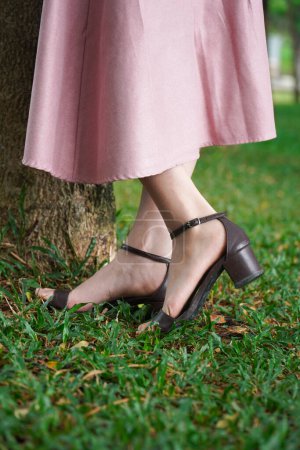 Photo for Close up of woman feet in summer. sandals shoes. high heels. with fresh green grass. beside the tree - Royalty Free Image