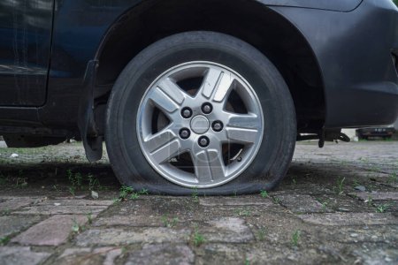 pneu de voiture à plat dans le parking, texturé avec des briques. semble avoir été abandonné