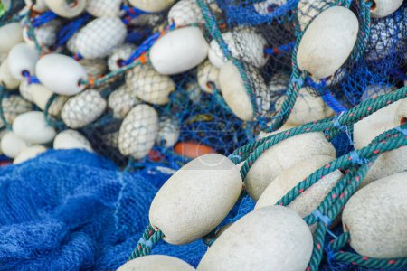 Téléchargez les photos : Pile de filet de pêche bleu avec flotteurs blancs. Filet de pêche et flotteurs de chalutier. Filets et cordes de pêche. outil pour attraper le poisson - en image libre de droit