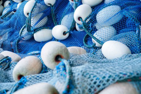 Foto de Pila de red de pesca azul con flotadores blancos. Red de pesca de arrastre y flotadores. Redes de pesca y cuerdas. herramienta para la captura de peces - Imagen libre de derechos