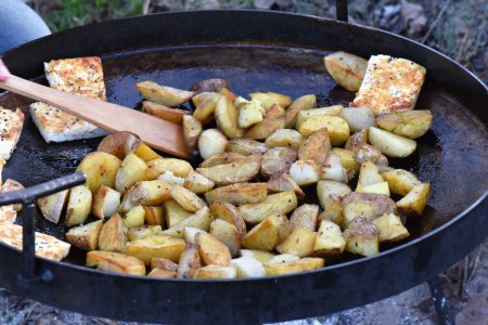 Fried potatoes and cottage cheese in a pan on the grill. Vegetarian food