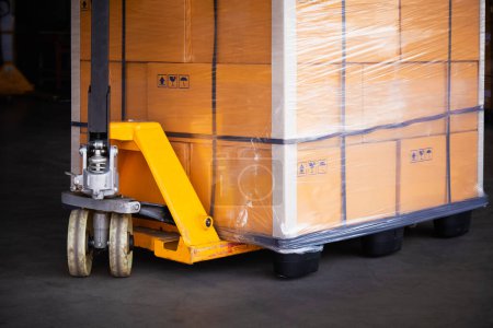 Photo for Hand Pallet Truck with Packaging Boxes Wrapped Plastic Stacked on Pallets. Hand Lift, Pallet Jack Loader Cartons, Cardboard Boxes. Shipment Goods. Shipping Cargo Supplies Warehouse Logistics. - Royalty Free Image