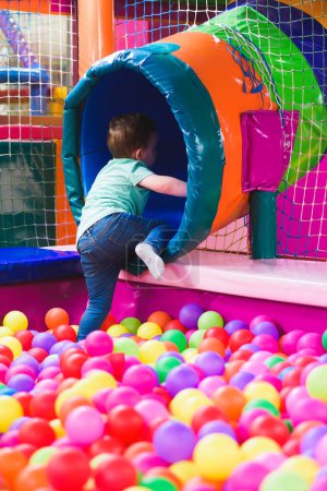 garçon sur l'aire de jeux avec des boules en plastique colorées.