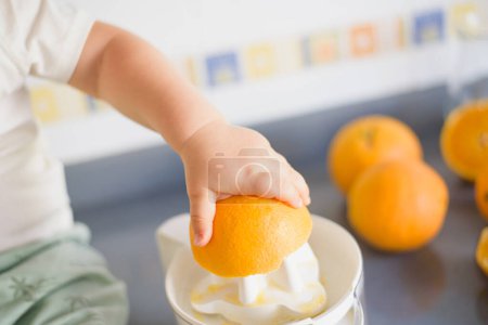 Photo for A girl child makes freshly squeezed orange juice on a manual juicer. - Royalty Free Image