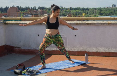 Foto de Mujer joven haciendo ejercicio de estiramiento de verano desde la azotea de su edificio - Imagen libre de derechos