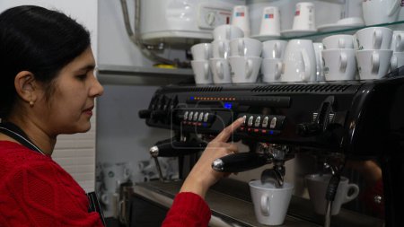 Foto de Mujer joven barista haciendo delicioso café en máquina de café expreso - Imagen libre de derechos