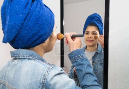 Foto de Mujer joven que se pone maquillaje delante del espejo en su habitación - Imagen libre de derechos