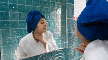 Foto de Mujer joven en el baño masajeando su cuello delante del espejo - Imagen libre de derechos