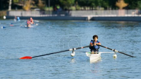 Boy training rowing in a lake near his house