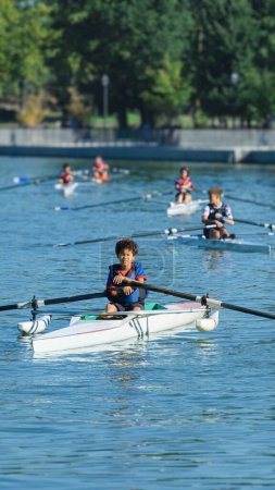 Boy training rowing in a lake near his home with his classmates