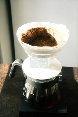 Photo for Black coffee freshly poured through a V-60 dripper into a gleaming glass decanter - Royalty Free Image