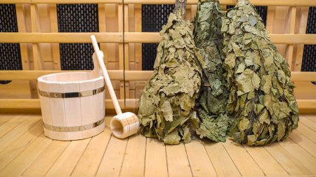 Ramos de escobas de abedul en la sauna en la pared de madera. Foto de alta calidad