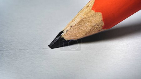 El lápiz dibuja una línea negra sobre un primer plano de papel blanco. Foto de alta calidad