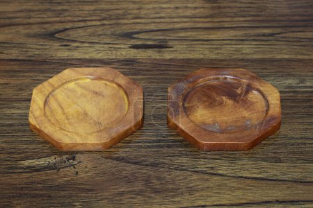 son dos posavasos de madera sobre mesa de madera.