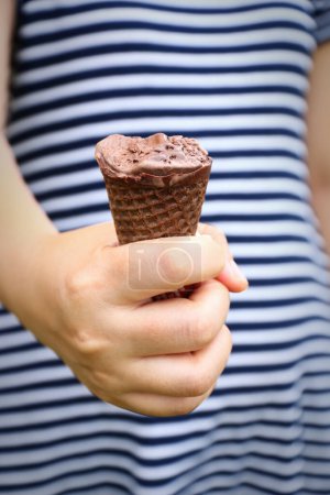it is lady hand holding melted chocolate ice cream and missing bite.