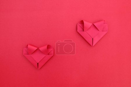 es dos corazones separados de papel rojo plegable en rojo para el patrón y el fondo.