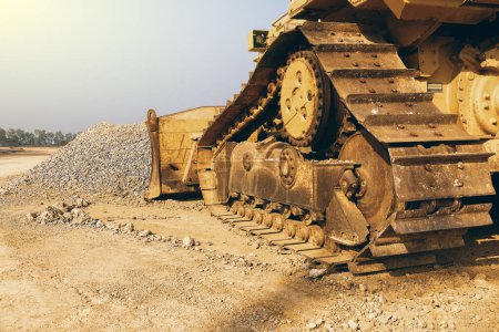 it is construction caterpillar tractor working with pile of gravel and sky.