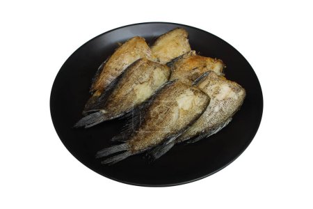 fried fish without its head on circle black plate isolated on white.