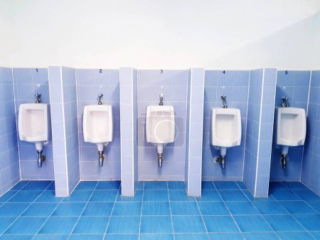 Photo for Five white urinal on blue wall with tile in men toilet or Public rest room. Object, Interior design and Sanitary ware concept - Royalty Free Image