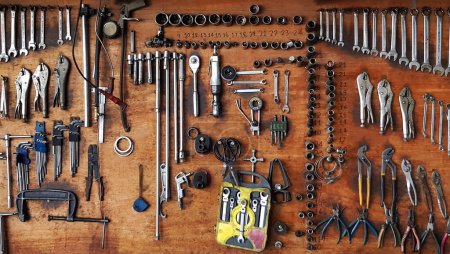 Viele verschiedene Größen von Werkzeugen, Schraubenschlüsseln und Zangen hängen auf Holzplatten Hintergrund. Werkzeug und Objekt zur Befestigung von Wartungs- oder Reparaturarbeiten an Auto, Maschine oder Motorrad