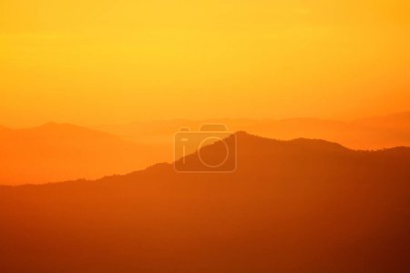 Beautiful orange sunlight or sunrise in morning with silhouette of big mountain for background at Doi Chiang Dao, Doi Luang Chiang Dao, Chiangmai, Thailand. Landmark and Beauty of Nature concept