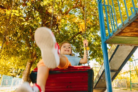 Photo for A beautiful and small girl swings with great safety and care on the specially arranged playground. High quality photo - Royalty Free Image