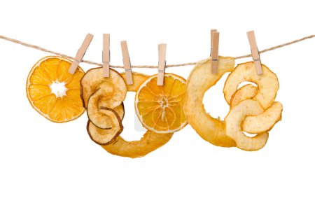 Téléchargez les photos : Tranches d'orange et de pomme séchées sur corde à linge isolées sur fond blanc - en image libre de droit