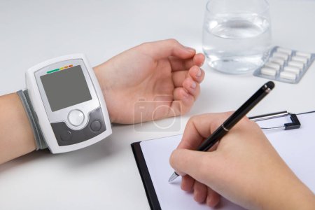 Foto de La mujer comprueba la presión arterial con un tonómetro. Tonómetro automático en la muñeca - Imagen libre de derechos
