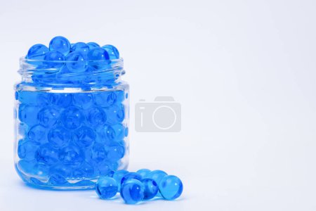 Blue orbeez in a glass jar on a light background. Selective focus.