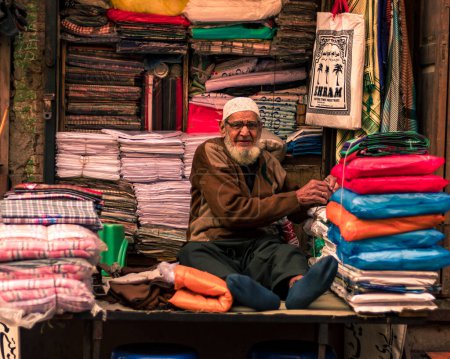 Foto de Lahore Pakistan 2020, an old man selling cloths in his small cloth shop in the walled city of Lahore, old man smiling and looking into the camera - Imagen libre de derechos