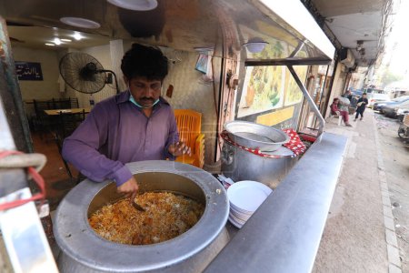Téléchargez les photos : Burns Road mars 2021, Un jeune homme vendant biryani à la célèbre et vieille rue de la nourriture de Karachi, restaurants de Karachi. - en image libre de droit
