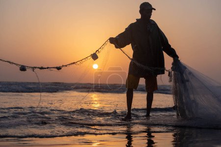 Téléchargez les photos : Karachi pakistan 2021, un pêcheur tirant un filet de pêche pour attraper du poisson, vue sur la mer en soirée. - en image libre de droit