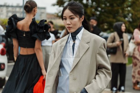 Téléchargez les photos : Un invité porte un blazer gris surdimensionné, une chemise blanche à boutons longs, vue devant le défilé PRADA pendant la Fashion Week de Milan Vêtements Femme Printemps / Eté 2024. - en image libre de droit