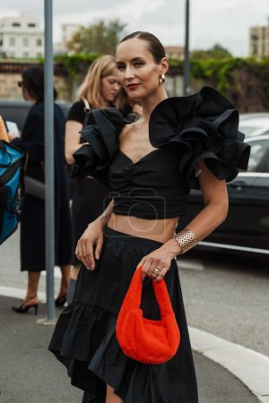 Téléchargez les photos : Un invité porte des boucles d'oreilles, un haut noir et une jupe, un sac rouge moelleux, vu à l'extérieur du défilé PRADA pendant la Fashion Week de Milan Vêtements Femme Printemps / Eté 2024. - en image libre de droit