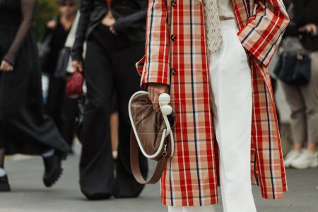 Téléchargez les photos : Un invité portant un trench-coat à carreaux, un pantalon blanc, une cravate et un sac marron, vu devant le défilé PRADA lors de la Fashion Week de Milan Vêtements Femme Printemps / Eté 2024. - en image libre de droit