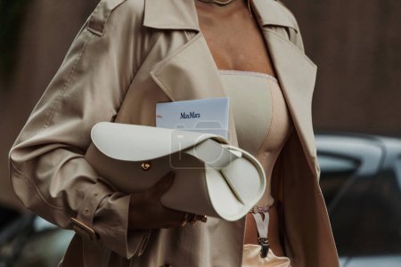 Téléchargez les photos : Détails de mode. Giulia Gaudino portant une tranchée beige clair, un haut beige, une jupe longue en soie beige, un sac en cuir crème blanc, vue à l'extérieur du défilé MAX MARA lors de la Fashion Week de Milan Vêtements Femme Printemps / Eté 2024. - en image libre de droit
