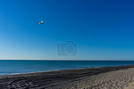Photo for MALAGA, SPAIN - MARCH 25, 2023: Airplane landing at sunrise over Mediterranean Sea, Costa del Sol in Malaga, Spain on March 25, 2023 - Royalty Free Image