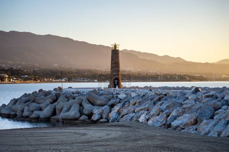 Photo for BANUS, SPAIN - MARCH 16, 2024: Lighthouse in marina on sunrise in Banus, Marbella, Spain on March 16, 2024 - Royalty Free Image