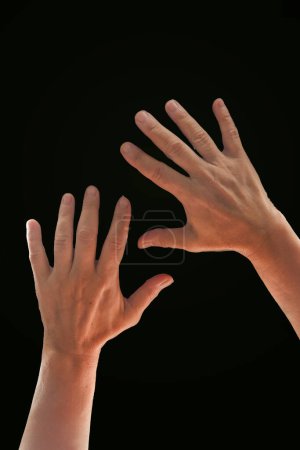 Téléchargez les photos : Mains avec les doigts écartés sur un fond noir. - en image libre de droit
