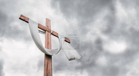 Christian cross on grey cloudy sky background announces Jesus's rising from the dead. Resurrection day concept.