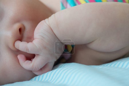 Téléchargez les photos : L'image capture un moment mignon d'un nouveau-né tentant d'explorer en mettant un doigt dans leur nez, mettant en valeur leur curiosité et leur développement moteur précoce - en image libre de droit