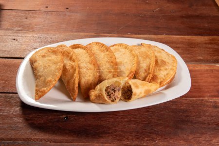 Photo for Fried Pastries, Pastel Frito Brasileiro, on wooden table. Pastel de carne - Royalty Free Image